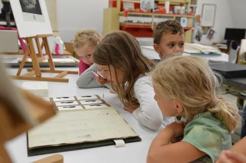Kinder schauen sich Zeichnungen in einem Buch an (Foto: Kurpfälzisches Museum)
