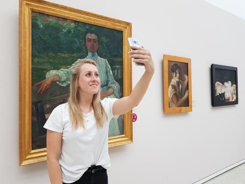 Eine junge Frau macht ein Selfie vor einem Gemälde. (Foto: Seele)