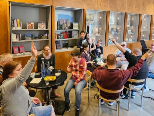 Museumscafé im Foyer Kurpfälzisches Museum, Foto: KMH Wer macht beim Podcast mit? Die Gruppe der Interessenten sitzt für diese Entscheidung im Museumscafé.Fast alle heben die Hand.